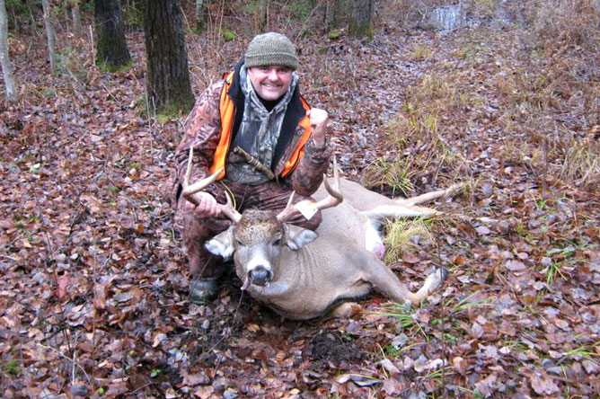 Homme montrant le cerf de Virginie qu'il vient d'abattre.