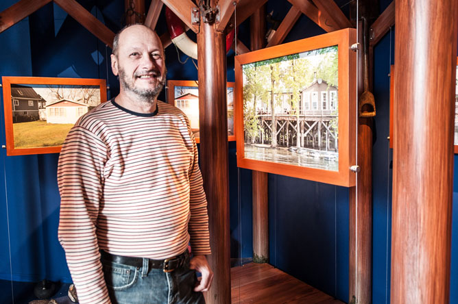 Un homme montre des photos de chalets sur pilotis.