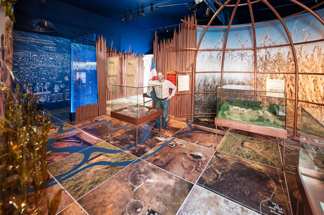 A man standing behind a display showing Iroquoians artifacts.