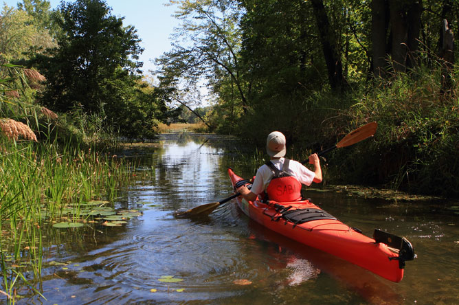 A young man paddles a kayak towards Baie de Lavallière.