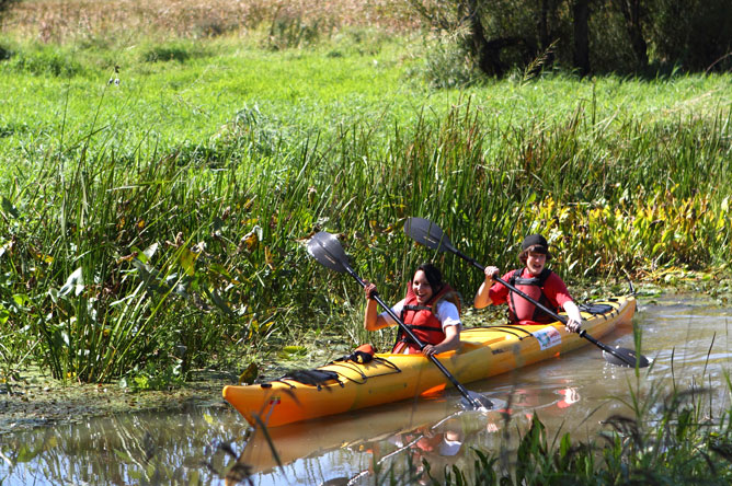 A boy and a girl share a kayak on Baie de Lavallière.