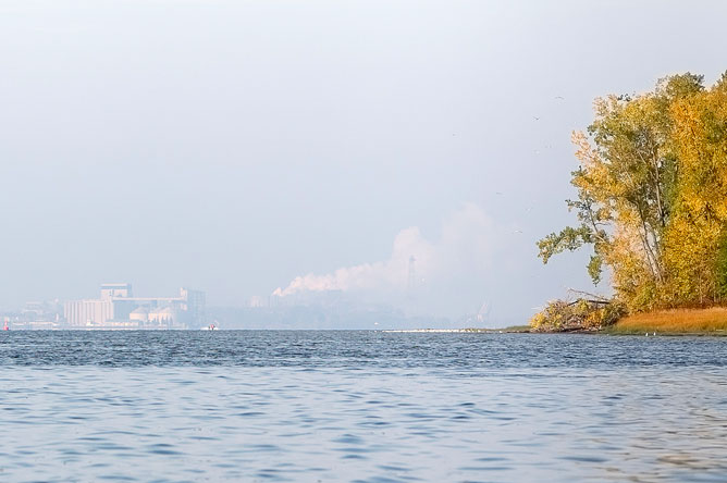 Smokestacks of the factory silhouetted against the horizon, seen from the archipelago.