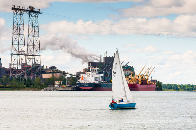 Sailboat on the St. Lawrence and ship moored at the Rio Tinto Fer et Titane wharf on the St. Lawrence.