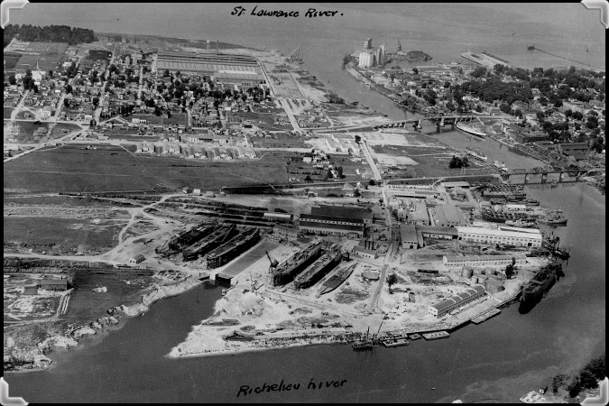 Photo aérienne en noir et blanc du chantier naval de Marine Industries Limited où on voit six navires en construction.