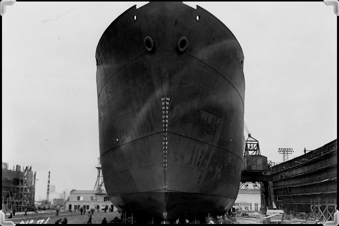 Men standing in front of a ship in the Marine Industries Limited shipyard, July 18, 1942.