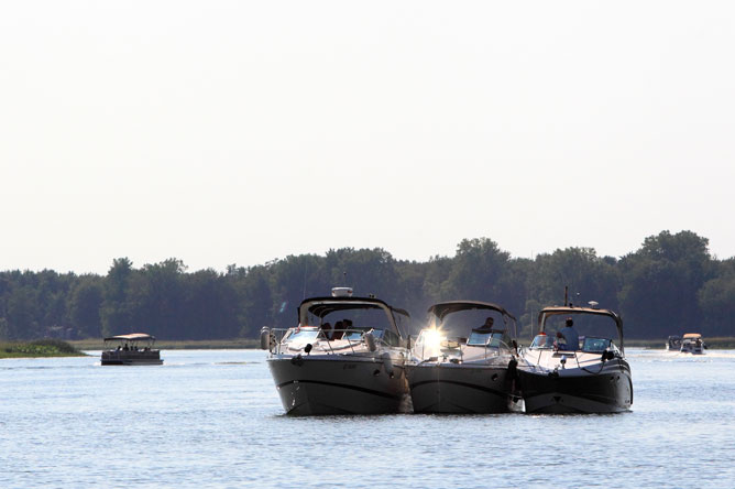 Three pleasure craft roped together in a channel.