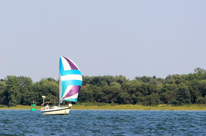 Voilier dans le chenal de navigation près d'une bouée verte