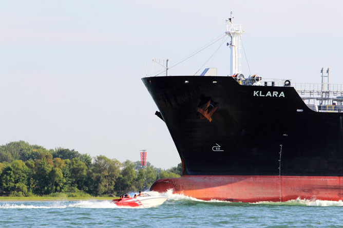 An imposing commercial vessel crosses paths with a pleasure boat on the St. Lawrence.