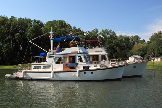 Two pleasure craft roped together in a channel.