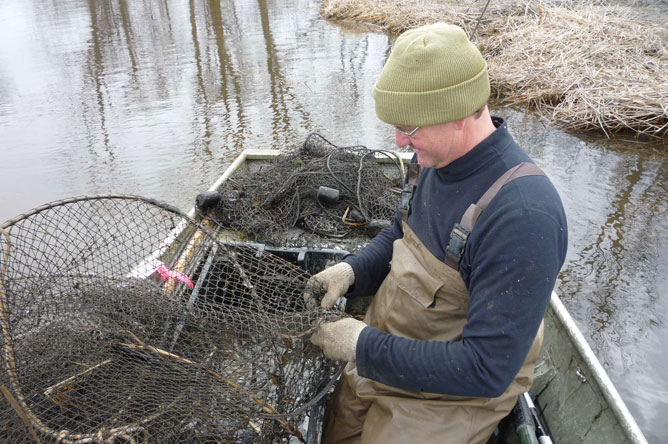 A man in a boat sets up a hoop net.