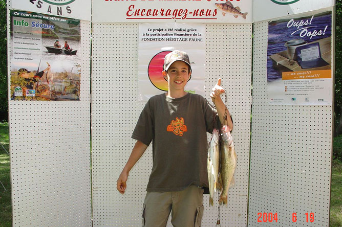 A young boy shows off the two Walleyes he has landed.