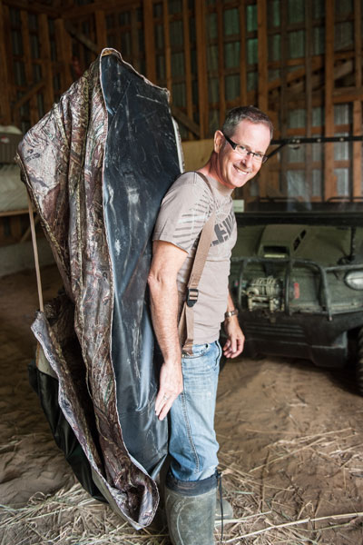 A man carrying a cloth blind on his back.