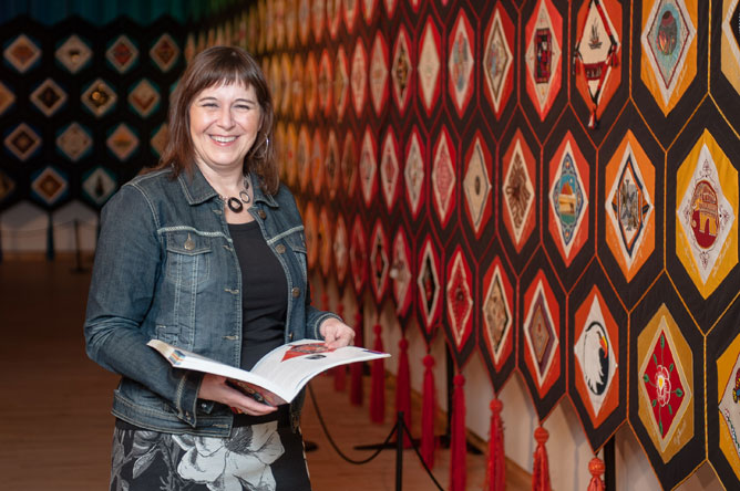 Michelle Bélanger, director of the Musée des Abénakis, in front of the colourful textile art project 'Quilt of Belonging'
