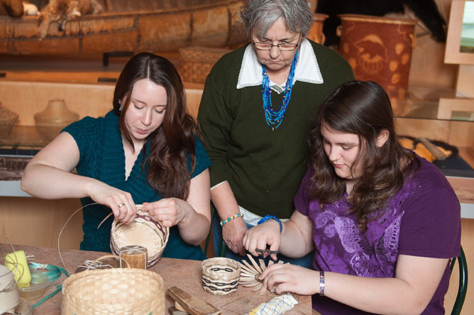 A woman and her two granddaughters weaving baskets.