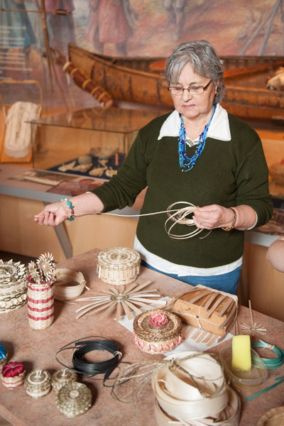 A woman standing behind a table and waving a basket.