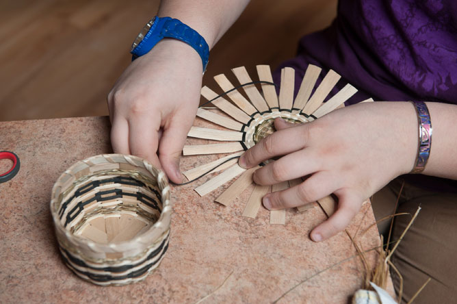 Close-up of a basket weaver's hands as she makes a basket.