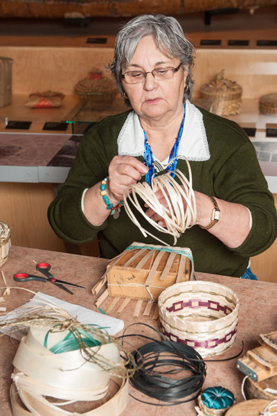 A woman sitting behind a table and waving a basket.