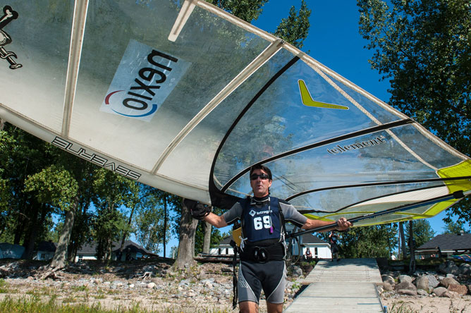 Un homme transportant une voile, transparente et vert pâle, au-dessus de lui.