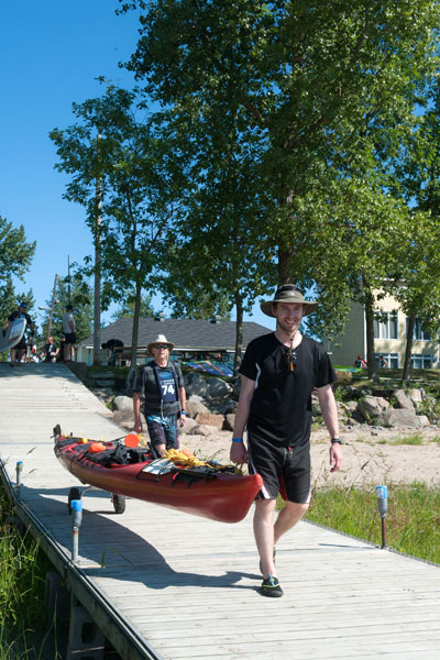 Two men carrying a kayak on a dock.