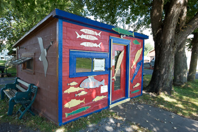 Cabane en bois rouge et bleue décorée de silhouettes de poissons multicolores.