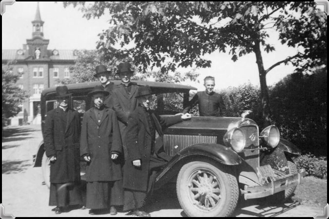 Six men stand near a car in front of the Novitiate of the Montfortain Fathers in Nicolet, 1937.