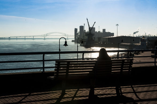 Person seated on a bench facing the St. Lawrence in Trois-Rivières.