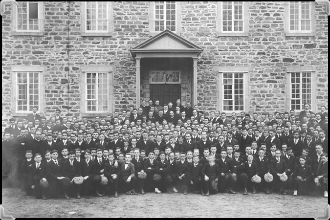 Photo en noir et blanc montrant des centaines d'élèves devant la façade en pierres du Séminaire de Nicolet.