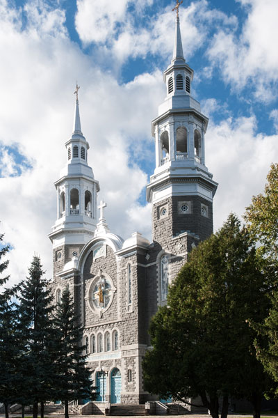 Large trees in front of an old gray stone church