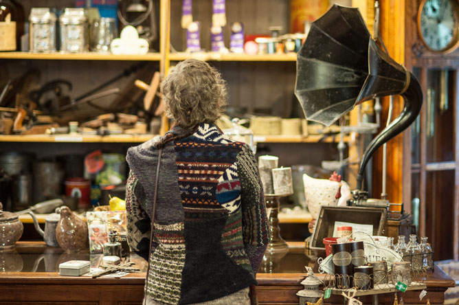 Une femme devant un comptoir du Magasin général Le Brun sur lequel est posé un gramophone