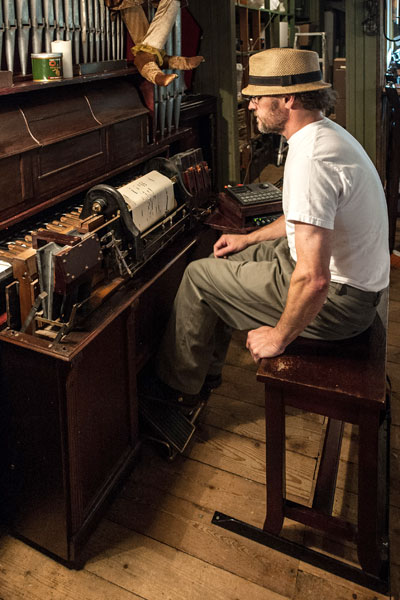 Man playing an antique musical instrument: the pianola