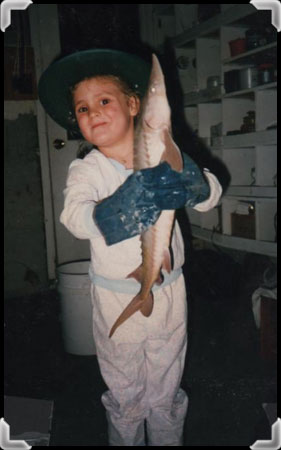 Girl wearing a hat and holding a juvenile sturgeon.