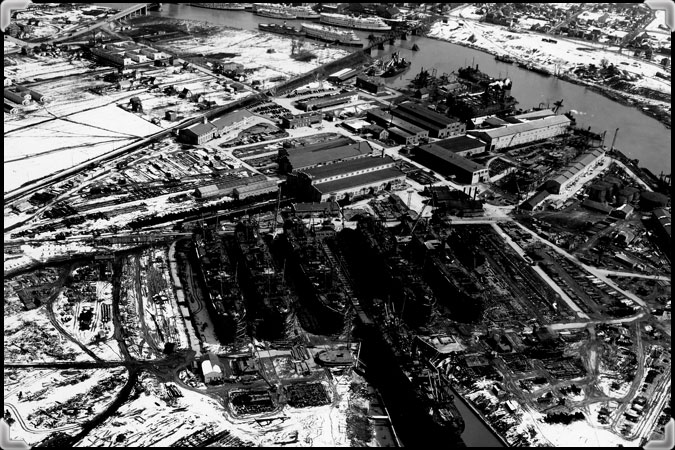 Photo aérienne en noir et blanc plus rapprochée du chantier naval de Marine Industries Limited où on voit six navires en construction.