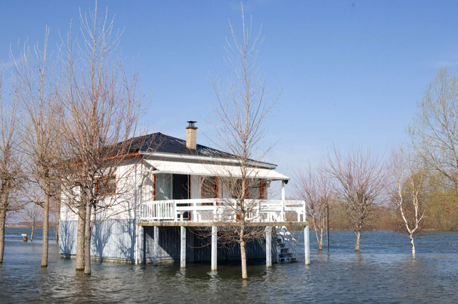  Chalet blanc et gris sur pilotis lors d'une inondation printanière